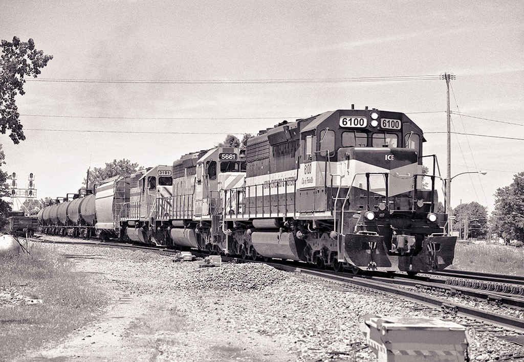 Stop Go Crossover Repeat
Iowa, Chicago and Eastern 6100 leads lessors back into motion, 
crossing from the north to the south main after having stopped to
wait for a westbound to pass on the west side of Deshler, Ohio.

June 12, 2011
