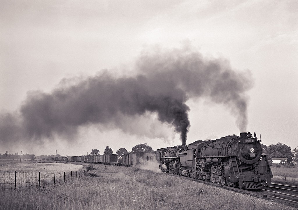 Westbound Twofer
GTW 6350 leads 2332 and a rider car west out of Durand
with mixed freight.  About where the flat and tank are in
the middle of the train appears to be the Pittsburg Road
crossing.

July 9, 1948
