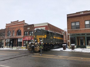 ADBF GP9 1760 is flagged across Grand River Avenue in Lansing, Old Town, to pickup the loaded scrap gon from Friedland Industries.