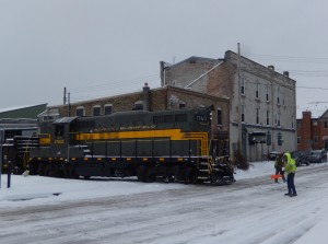 Having tied on to the N&amp;W gondola, the train rolls slowly north, being flagged across Clinton Street in the North Lansing Historic District.